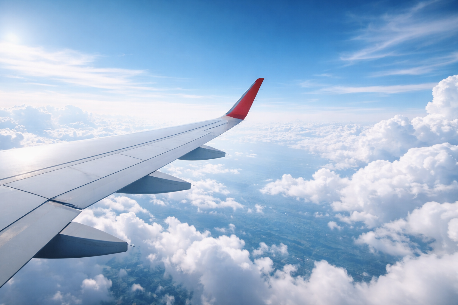 Airplane wing above the clouds representing travel and global destinations.